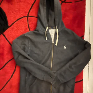 Mörkgrå hoodie från Polo Ralph Lauren - Mörkgrå hoodie från Polo Ralph Lauren med vit broderad logga på bröstet.  Zipper saknas