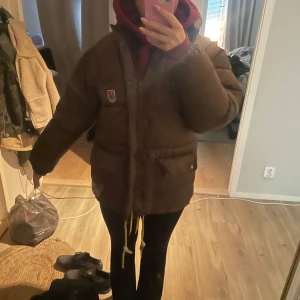 Brun pufferjacka från Fjällräven - Säljer en brun pufferjacka från Fjällräven med klassisk logga på bröstet. Jackan har en oversized passform, långa ärmar och praktiska fickor med dragkedja. Perfekt för kalla dagar med sin tjocka och quiltade design. Snygg och enkel att matcha med din stil. Kan vara flexibel med pris då den ändå är begagnad 