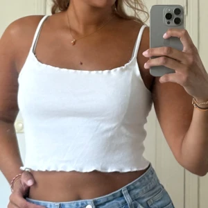 Vitt linne Brandy Melville - Säljer en vit croppad linnetopp från Brandy Melville. Toppen har smala axelband, rak halsringning och vågig kant. Tillverkad i 100% bomull 