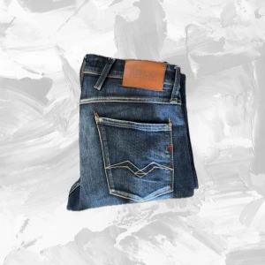 Replay Anbass jeans blå slim fit - Snygga blå Replay Anbass jeans med klassisk femficksdesign och coola slitningar. Jeansen har slim fit-passform och är tillverkade i mjukt denimtyg med stretch för extra komfort. Perfekta för dig som gillar en modern och stilren look.