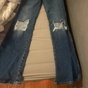 Blå bootcut jeans med slitna knän - Säljer ett par helt nya oanvända jeans från lager! Dom är lågmidjade!