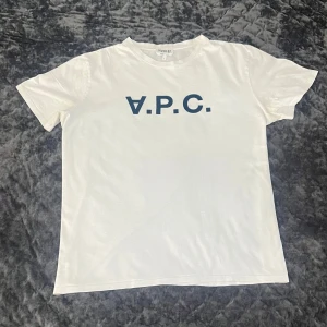 Vit A.P.C. T-Shirt - Tja! Säljer nu denna väldigt sällsynta och schyssta A.P.C. T-shirten! Storlek= L, Fits=M/L. Bra skick utan några tydliga defekter! A.P.C. Märket är i mocka vilket är högt eftertraktat! 100% Bommul i hög kvalité. Hiver 87 Collection vilket gör den ännu mer sällsynt! Hör av dig vid minsta fråga eller fundering!🌟