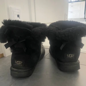 Svarta UGG boots med rosett - Säljer mina svarta uggs. Köpt förra året men vän använda. Storlek 37 men passar mig som har 38. Skulle kunna tänka mig att gå ner i pris!