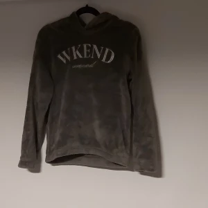 Mjuk grå hoodie med text från H&M - Supermjuk och fluffig grå hoodie från H&M med texten 'WKEND mood' på bröstet. Hoodien har långa ärmar och en huva med roliga ögon och små detaljer som gör den extra unik. Perfekt för chill dagar eller när du vill vara extra cozy.