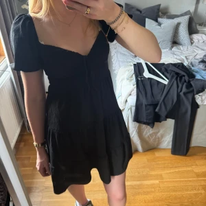 Svart klänning Gina Tricot - Säljer en svart klänning i storlek S från Gina Tricot. Den har diskreta puffärmar, en snörning vid bysten och en fin kjol. Den är i mycket bra skick. Hör gärna av dig vid frågor🤎