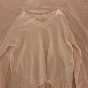 Beige stickad tröja från Vila - Mysig beige stickad tröja från Vila med v-ringad hals och bred ribbad kant vid halsringning och nederkant. Tröjan har långärmad passform och är perfekt för lager-på-lager-stil. Enkel och stilren design som funkar till många outfits. Skickar såklart bild om det skulle önskas. 