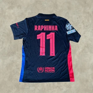 Barcelona ”RAPHINHA #11” 24/25 Borta - Säljer en Barcelona 24/25 bortatröja i storlek M med Raphinha #11 på ryggen. Tröjan har även Champions League-märke på ärmen och är i mycket fint skick.  Kan även gå ner i pris vid snabb affär