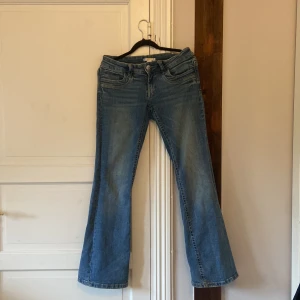Lågmidjade bootcut jeans från Gina Tricot - Snygga blå jeans från Gina Tricot i bootcut-modell. Jeansen här i storlek 158 men passar som S. Lite slitningar vid ena foten.