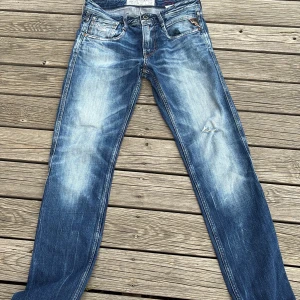 Replay blå jeans straight fit - Snygga blå jeans med snygg slitage.  längd w 29 längd  32 från Replay med slitningar och ljusa partier. (Stonewash) Jeansen har ett litet hål i en av innerfickorna men det påverkar inte jeansens funktion. 
