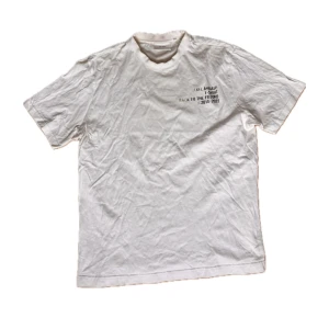 Vit Axel Arigato t-shirt med tryck - Snygg vit t-shirt från Axel Arigato med coolt tryck på bröstet: 'Back to the Future ©2014-2022'. Klassisk passform och rund hals. Materialet är mjuk bomull som känns skönt mot huden. Perfekt för dig som gillar minimalistisk stil med en twist.