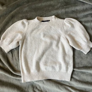 Vit stickad tröja från Vero Moda - säljer en superfin krämvit kortärmad stickad tröja från Vero Moda i storlek XS, perfekt nu till hösten!!🍁💓tröjan har puffiga korta ärmar och ribbade muddar vid hals, ärmslut och nederkant. något nopprig men inget man tänker på. skriv vid fler frågor💓💓