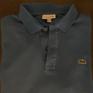  piké Lacoste - Snygg blå pikétröja från Lacoste i slim fit-modell. Storlek L. Skriv vid frågor eller funderingar.