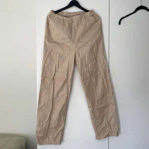 Beiga vida byxor från NLY Trend - Snygga beiga byxor från NLY Trend i storlek 36. De har en relaxed fit med resår i midjan och raka, vida ben. Perfekta för en chill och stilren look. Materialet känns lätt och luftigt, vilket gör dem sköna att bära hela dagen.