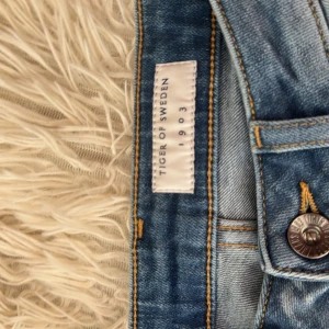 Ljusblå jeans från Tiger of Sweden - Säljer ett par ljusblå jeans från Tiger of Sweden med klassisk femficksdesign och snygga kontrastsömmar. Jeansen har en normal passform och är tillverkade i slitstarkt denimtyg. Perfekta för dig som gillar stilrena och tidlösa jeans.
