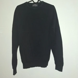 Svart bomullströja Hampton Republic - En stilren svart tröja från Hampton Republic i mjuk bomull. Klassisk rund halsringning och ribbade muddar vid ärmslut och nederkant. Perfekt för dig som gillar en enkel och clean look. Passar till det mesta och är lätt att matcha.