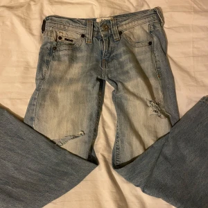 Ljusblå baggy jeans från urban outfitters  - Baggy ljusblå jeans från urban outfitters  med slitna detaljer och hål på benen som jag själva har klippt men du kan sy ihop. Jeansen har låg midja, raka ben och klassisk femficksdesign. Perfekta för en avslappnad och trendig look. Materialet är klassisk denim i bomull.