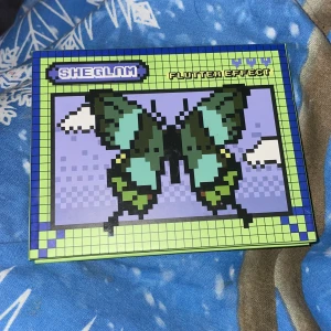 SHEGLAM Flutter Effect ögonskuggspalett - ‼️Använd någon enstaka gång men i övrigt orörd‼️ Säljer en SHEGLAM Flutter Effect ögonskuggspalett med 12 färger inspirerade av fjärilar. Paletten har nyanser i blått, grönt, lila och glitter, både matta och skimrande. Kartongförpackning med pixelart-design och spexiga namn på varje skugga. 100% vegansk och cruelty-free. 