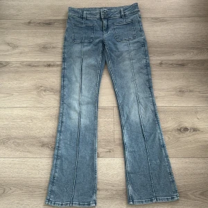 Blå bootcut jeans från Gina Tricot - Snygga ljusblå bootcut jeans från Gina Tricot med raka sömmar längs benen och stora fyrkantiga fickor fram. Jeansen har bälteshällor och klassisk knappstängning. Perfekta för dig som gillar retrovibbar och en avslappnad stil. aldrig använda bara testade💞