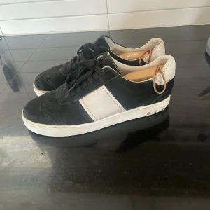 Valentino flycrews - Snygga sneakers från Valentino i svart mocka och vitt skinn. Klassisk design med svarta snören och vit rand på sidan. Perfekta för dig som gillar stilrena och exklusiva skor med en sportig touch.