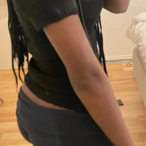 Svart ribbad stickad topp - Snygg stickad svart T-shirt med ribbade ränder och. Modellen är slim och har en rundad halsringning. Materialet är mjukt och stretchigt, perfekt för dig som gillar en enkel men snygg look. 