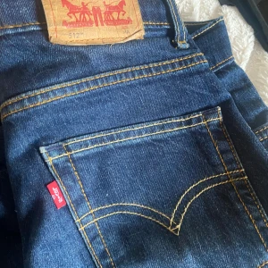 Levi's 512 Slim Taper jeans blå - Snygga Levi's 512 Slim Taper jeans i mörkblå denim med klassiska kontrastsömmar och fem fickor. Modellen har smal passform med avsmalnande ben och ikonisk röd Levi's-tag vid bakfickan. Perfekt för dig som gillar en modern och stilren look. Billigare vid snabb affär.