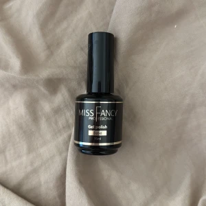 Miss Fancy Gel Polish Base 15ml - Gel polish base från Miss Fancy Professional i en snygg svart flaska med silverdetaljer. Innehåller 15 ml och är perfekt som grund för gelnaglar. Flaskan har en rund form och är tillverkad av plast med en stilren look. Oanvänd!!