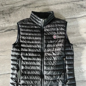 Svart dunväst från Colmar - Snygg svart dunväst från Colmar med quiltad design och dragkedja framtill. Västen har två praktiska fickor med dragkedja och en hög krage. Perfekt för lager-på-lager och enkel att matcha med olika outfits. Pris kan diskuteras