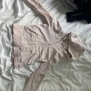 Ljusrosa hoodie från H&M YOUNG - Mysig ljusrosa hoodie från H&M YOUNG med dragkedja framtill och två fickor. Tröjan har huva och är tillverkad i mjuk bomullsfrotté, perfekt för chill dagar. Långärmad och enkel att matcha med jeans eller leggings.