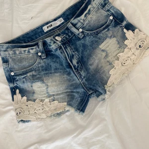 Jeansshorts med spets  - Snygga blå jeansshorts från FBSister med slitna detaljer. Coola kontraster med fina spetsdetaljer. Köpt secondhand men har aldrig använt då de inte passar mig. Priset är inte hugget i sten