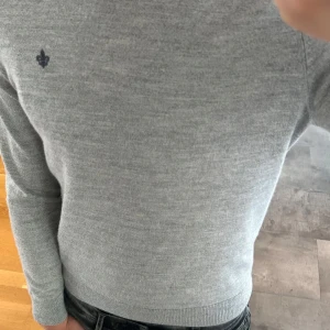 Grå merinoulltröja från Morris  - Säljer en stilren grå stickad tröja från Morris i 100% merinoull. Tröjan har rund hals, lång ärm och en liten mörkblå logga broderad på bröstet. Perfekt för dig som gillar klassisk och clean look med premiumkänsla. Priset kan diskuteras 
