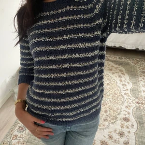 Randig stickad tröja i marinblått - Säljer en stickad tröja med marinblå och vita ränder. Tröjan har rund halsringning, trekvarts- ärmar och en skön, normal passform. Perfekt till jeans och enkel att styla för en chill look.