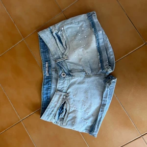 Ljusblå jeansshorts med pärldetaljer - Snygga ljusblå jeansshorts med pärldetaljer framtill. Klassisk femficksmodell, uppvikta benslut och låg midja. Perfekta för varma dagar och enkel att matcha med allt. Priset kan diskuteras!💗💗