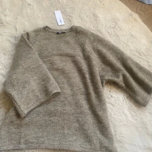 Oversized stickad tröja Gina Tricot - Mysig oversized stickad tröja från Gina Tricot i brunmelerad nyans. Tröjan har rund halsringning och vida trekvartsärmar, perfekt för lager-på-lager och chill vibes. Passar dig som gillar en loose och avslappnad stil. Sista bilden fick konstigt ljus