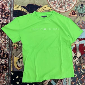Grön t-shirt från Tommy Hilfiger - Snygg grön t-shirt från Tommy Hilfiger med diskret logga framtill. Klassisk passform med rund hals och korta ärmar. Perfekt för dig som vill sticka ut med en färgstark look. Materialet är mjuk bomull som känns skönt mot huden.