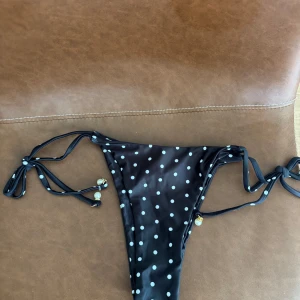 Svart bikini med vita prickar - Snygg svart bikini med vita prickar och knytband i sidorna samt i nacken.