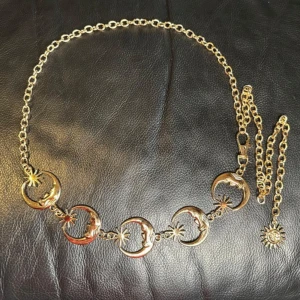 Kedjebälte i guldfärgad metall med månar & solar – boho/witchy stil - Magiskt kedjebälte i guldfärgad metall med detaljer av månskäror och solar. Justerbar längd (ca 110 cm), stängs med karbinhake och har en dekorativ solberlock. Perfekt accessoar för dig som gillar boho, goth eller witchy stil – lyfter varje outfit med en mystisk touch. Ingen prutning – priset är redan lågt, men jag erbjuder rabatt vid köp av flera saker. Jag rensar garderob och smyckesskrin – spana gärna in mina andra annonser också!  ⸻ 