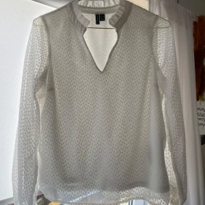 Vit blus - Vit blus med små volanger vid kragen. Har små prickiga broderi detaljer. Använd men inga skador. 
