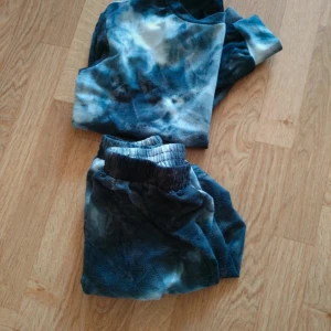 Blå tie-dye fleece tröja - Mysig långärmad tröja i blå och vita tie-dye nyanser. Tillverkad i mjuk fleece som känns skön mot huden. Perfekt för chill dagar hemma eller när du vill ha något riktigt bekvämt. Tröjan har en avslappnad passform och elastiska muddar vid ärmsluten.