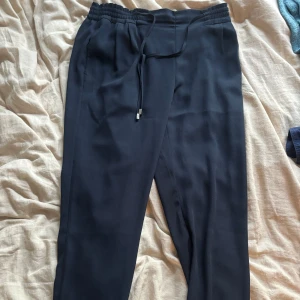 Svarta byxor från Zara Basic M - Snygga mörkblå byxor från Zara Basic i storlek M. Byxorna har elastisk midja med dragsko, raka ben och diskreta fickor både fram och bak. Perfekta för en chill och stilren look. Materialet känns mjukt och lätt, passar till många outfits.
