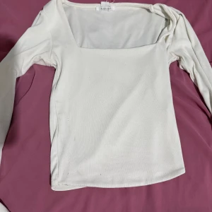 Vit långärmad topp med fyrkantig ringning - Säljer en stilren vit långärmad topp från EUIJUSICA i storlek XS. Toppen har en snygg fyrkantig ringning och är gjord i ett mjukt, ribbat material som sitter skönt mot kroppen. Perfekt att matcha med jeans eller kjol för en clean look.