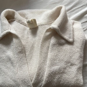 Vit stickad T-shirt klänning  - Vit stickad sommrig t-shirt klänning från H&M med klassisk krage och v-ringning. Otroligt luftig och sval. Perfekt att dra på sig innan eller efter stranden. 