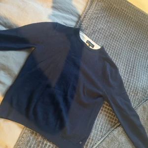 Mörkblå Kashmir tröja från Lagency - En klassisk mörkblå stickad tröja från Lagency med rund halsringning. Tröjan har en enkel och stilren design, perfekt att matcha med jeans eller chinos. Långärmad och mjuk i materialet för en skön känsla hela dagen. Nypris 1200