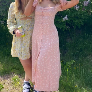 Ljusrosa blommig långklänning med puffärm - Säljer billigt pga en defekt, se sista bilden: det saknas en knapp och därav har sömmen gått upp, jag har både sytt och limmat med tyglim, men ibland syns ett litet hål där knappen ska vara, som på sista bilden! En ny knapp medföljer💕