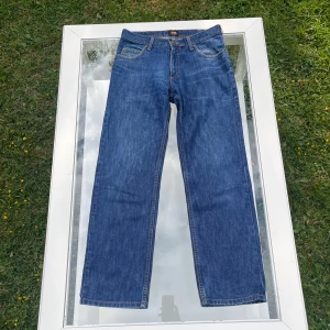 Lee Jeans Brooklyn - Säljer ett par Lee Brooklyn Straight Jeans i klassisk mellanblå tvätt. Storlek W31 L30. Rak passform med normal midja. Mycket fint skick, knappt använda, inga hål, fläckar eller defekter. Pris går att diskutera. Bara att höra av dig vid minsta fundering!