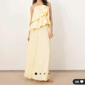 Ljusgul axelbandslös långklänning - En superfin klänning från märket Arrange som säljs via Asos. Har två stycken, en i storlek 40 och 42. Denna annons gäller storlek 42. Helt oanvänd med lappar i originalförpackning.  (Köpte flera storlekar och hann inte returnera i tid därav att jag har flera) Överdelen är i lite mer stabilt tyg och kjolen ör underbart flowy och mjuk.  Nypris 2279 kr. Går att se video på ASOS sök på Arrange origami. 