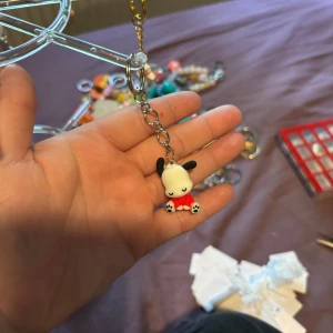 Nyckelring med söt kaninfigur - Nyckelring med en gullig kaninfigur i vitt och svart med röda byxor och små tassar. Perfekt accessoar till väskan eller nycklarna för dig som gillar söta detaljer.