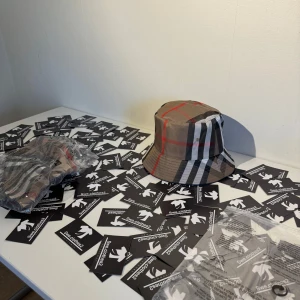 Burberry rutig bucket hat beige - Snygg bucket hat från Burberry i klassiskt rutigt mönster med beige, svart, vitt och röda detaljer. Hatten har en bred brätte och är tillverkad i bomull. Perfekt accessoar för att lyfta din outfit med en lyxig touch.