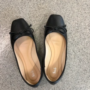 Svarta ballerinaskor med rosett  - Svarta ballerinaskor, använda endast en gång. Lite stora i storleken. De har skoskavsskydd bak i hälen. De är beiga och inget som syns!🤍pris går att diskuteras 