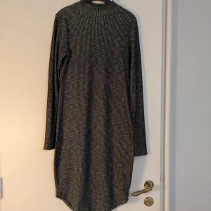 Randig ribbad klänning Gina Tricot - Ribbad klänning från Gina Tricot i storlek M. Med lång ärm, halvpolohals och figurnära passform. Materialet är mjukt och stretchigt med 50% polyester, 45% viskos och 5% elastan. Perfekt för dig som gillar enkel och stilren look. Svartgrå.