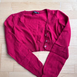 (Mörk)Röd croppad kofta med glittriga knappar - Snygg  croppad kofta från Violeta by Mango. Koftan har långa ärmar, ribbade muddar och glittriga knappar framtill som ger en extra touch. 